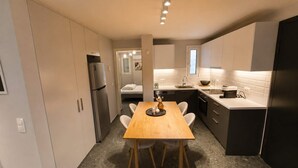 Cocina compacta con mesa, armarios y refrigerador.