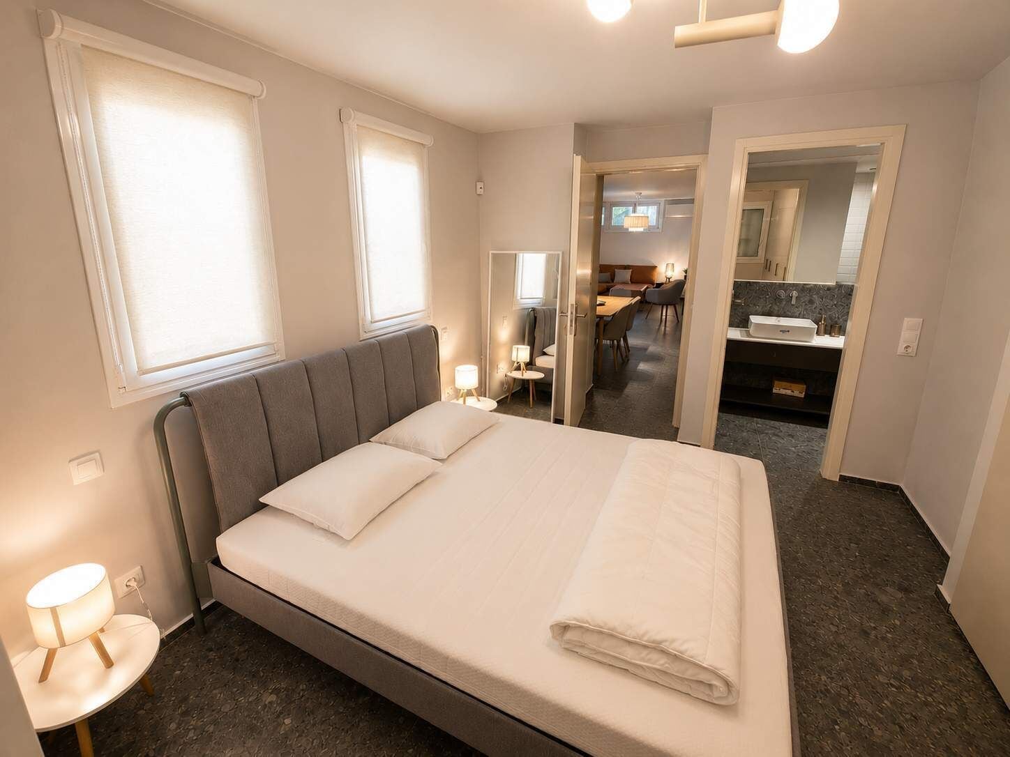 Une chambre d’hôtel avec un lit, des tables de chevet, un bureau et une salle de bain visible à travers une porte ouverte.