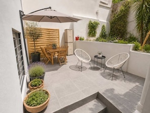 An outdoor patio with a wooden table and chairs, a white umbrella, and potted plants. - Boutique 2Bd Oasis in Lycabettus with Garden Patio (Athina)