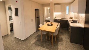 Una cocina moderna con una mesa de comedor, sillas, un refrigerador y un lavamanos.