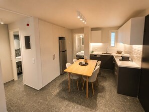 A modern kitchen with a dining table, chairs, a refrigerator, and a sink. - Boutique 2Bd Oasis in Lycabettus with Garden Patio (Athina)