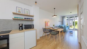 A modern kitchen with a microwave, coffee maker, and a dining area with a table and chairs. - Apartamenty Sun & Snow LEMON (Władysławowo)