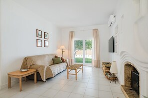 A living room with a sofa, a small table, a bench, a fireplace, and a TV mounted on the wall. - Villa Sousa by Dreamplaces (Albufeira)