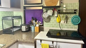 Een keuken met een granieten aanrecht, een waterkoker, een vergiet en een afdruiprek.