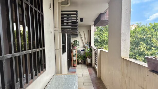 Een balkon met een metalen hekwerk, plantenbakken en een tafeltje.