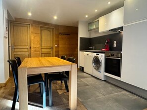 Una cocina moderna con una mesa y sillas de madera, una lavadora y un horno empotrado.