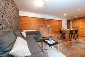 Ein stilvolles Wohnzimmer mit einem grauen Ecksofa, einem kleinen Couchtisch und einer Holzkommode.