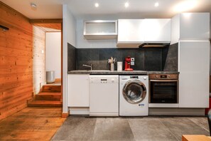 A compact kitchen with a washing machine, oven, and a coffee maker. - Le Bel Alp - The Perfect Mountain Getaway (Les Deux Alpes)