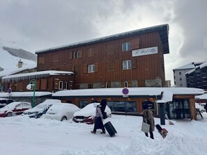 Un edificio con un letrero que dice 'Le Balconier' frente a un estacionamiento cubierto de nieve.