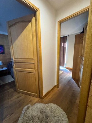 Una habitación con piso de madera, un tapete mullido y una puerta que da a otra habitación.