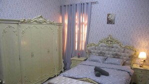 A bedroom with a large wardrobe, a bed with a tufted headboard, and a bedside table with a lamp. - العين الهيلي مصباح بيت 13 (Al Ain)