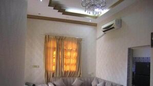 A living room with a sectional sofa, a coffee table, and a chandelier. - العين الهيلي مصباح بيت 13 (Al Ain)