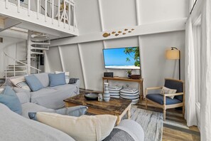 Ein modernes Wohnzimmer mit einer Couch, einem Couchtisch, einem Fernseher und einem Sessel.