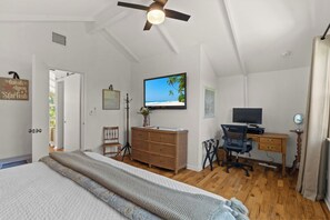 Ein Schlafzimmer mit einem Bett, einem Schreibtisch, einem Fernseher und einem Deckenventilator.