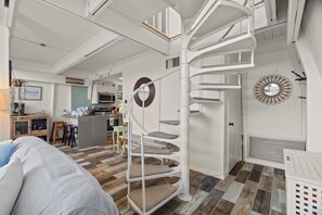 A modern interior with a spiral staircase, a kitchen area, and a living space with a sofa. - Coastal A-Frame Retreat | 2BR/2BA | 5-Min Walk to Beach |  Pet Friendly (Sanibel)