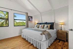 A bedroom with a bed, two windows, a nightstand, and a lamp. - Coastal A-Frame Retreat | 2BR/2BA | 5-Min Walk to Beach |  Pet Friendly (Sanibel)