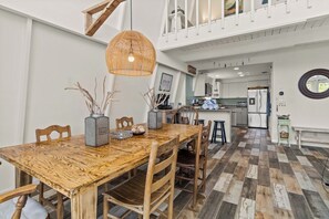 A dining area with a wooden table, chairs, and a hanging light fixture. - Coastal A-Frame Retreat | 2BR/2BA | 5-Min Walk to Beach |  Pet Friendly (Sanibel)