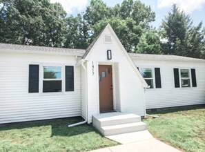 A single-story house with a small porch, a door, and a window.