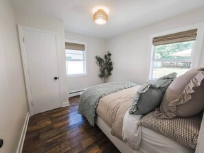 A bedroom with a bed, a door, a window, and a ceiling light fixture.