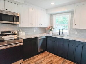 A modern kitchen with white cabinets, a stainless steel oven, and a dishwasher. - White Lake Cottage | Whitehall Lakeside Charm (Whitehall)