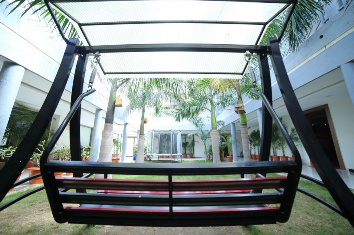 A covered outdoor seating area with a view of a building and palm trees.