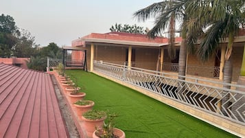 Eine Dachterrasse mit rotem Dach, einem grünen Rasen und einer weißen Brüstung.
