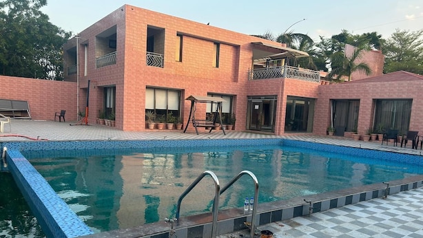 Uma piscina com piso xadrez, uma escada de metal e um edifício com varandas ao fundo.