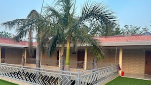 Um edifício com área externa coberta, palmeiras e varanda com grade.