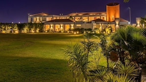 Um hotel moderno com um amplo gramado e uma torre cilíndrica imponente.