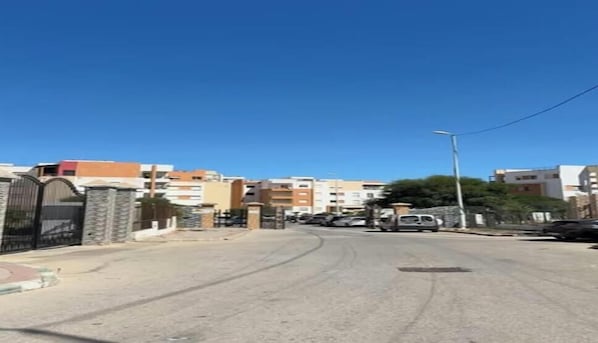 A street view with buildings, a clear sky, and parked cars.