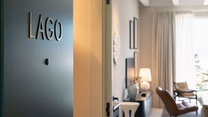 A hotel room with a door labeled 'LAGO' and a seating area with a chair and a table. - MC residence (Tremezzo)