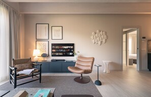 Ein modernes Wohnzimmer mit Ledersessel, Sofa, Couchtisch und einem flachbildfernseher an der Wand.