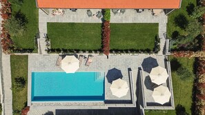 En vy från ovan av en fastighet med en swimmingpool, ett utomhusområde med sittplatser och en täckt uteplats.