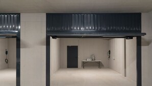 A room with a high ceiling, a door, and a table with a suitcase. - MC residence (Tremezzo)