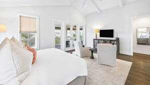 A bedroom with a bed, a chair, a TV, and a balcony. - Elegant Pet-Friendly Coastal Retreat with Private Pool, Cabana, & Elevator (Seacrest West)