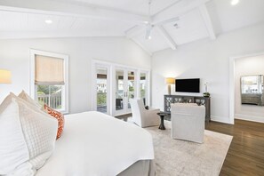 A bedroom with a bed, a chair, a TV, and a balcony. - Elegant Pet-Friendly Coastal Retreat with Private Pool, Cabana, & Elevator (Seacrest West)