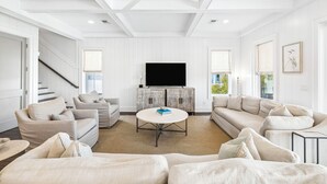 A modern living room with a flat-screen TV, two sofas, a coffee table, and a staircase. - Elegant Pet-Friendly Coastal Retreat with Private Pool, Cabana, & Elevator (Seacrest West)