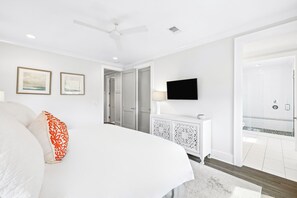 A hotel room with a bed, a television, a bathroom with a shower, and a ceiling fan. - Elegant Pet-Friendly Coastal Retreat with Private Pool, Cabana, & Elevator (Seacrest West)