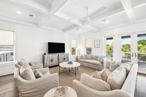 A spacious living room with a large flat-screen TV, a round coffee table, and a sofa set. - Elegant Pet-Friendly Coastal Retreat with Private Pool, Cabana, & Elevator (Seacrest West)