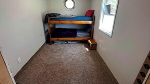 Ein kleines Zimmer mit einem Etagenbett, einem Fenster und Teppichboden.