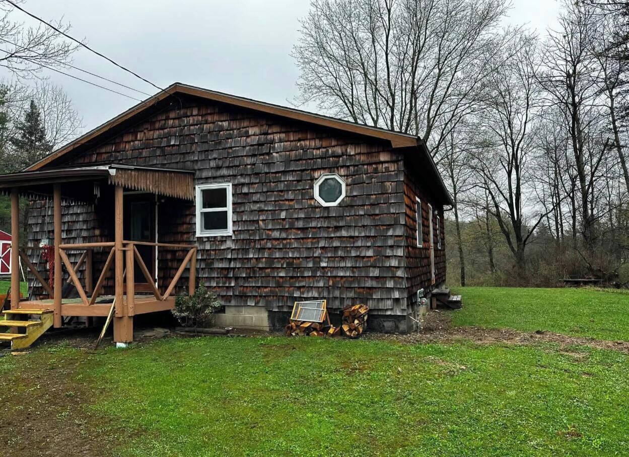 A rustic wooden cabin with a porch, a small window, and a door.