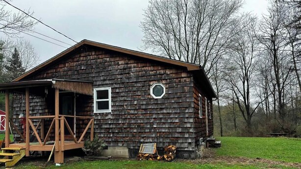 Eine rustikale Holzhütte mit Veranda, kleinem Fenster und Tür.