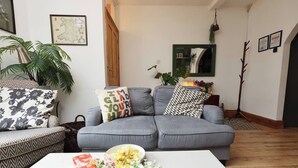 A living room with a grey sofa, a patterned armchair, a coffee table with flowers, and a television remote. - #02 Just the Splott! Sleeps 6, 8mins to Stadium. (Cardiff)