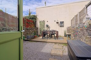 Eine Terrasse mit Tisch und Stühlen, eine Steinmauer und eine Holzbank.