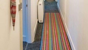Ein Korridor mit Streifenmusterteppich, einem Heizkörper und einer Tür zu einem Zimmer.