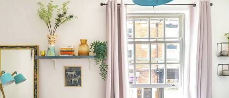 Une pièce avec une grande fenêtre, un radiateur, un miroir et une lampe bleue.
