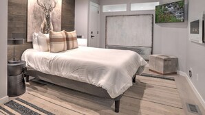 A modern bedroom with a large bed, a wall-mounted artwork of a deer head, and a large window. - Mountain Modern Condo | AC, Pool, Hot Tub, Golf & Ski (Durango)