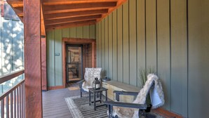 A wooden porch with a bench and a table, a door with a number, and a view of the outside. - Mountain Modern Condo | AC, Pool, Hot Tub, Golf & Ski (Durango)
