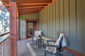 A wooden porch with a bench and a table, a door with a number, and a view of the outside. - Mountain Modern Condo | AC, Pool, Hot Tub, Golf & Ski (Durango)