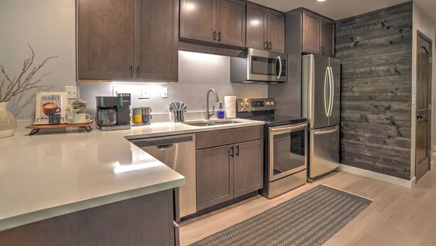 A modern kitchen with stainless steel appliances, wooden cabinets, and a built-in microwave. - Mountain Modern Condo | AC, Pool, Hot Tub, Golf & Ski (Durango)